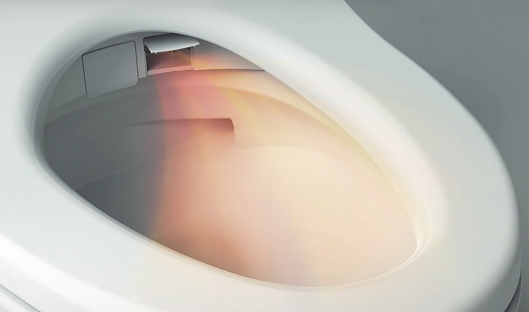Auf dem Bild ist ein Washlet abgebildet, die Klappe rechts neben der Düse ist geöffnet. Aus ihr kommt ein Luftstrahl, er ist gebogen und orange/rot eingefärbt.
