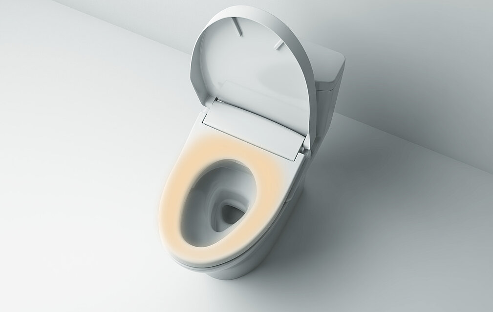 Auf dem Bild ist ein Washlet von oben abgebildet. Der Deckel ist geöffnet. Die Sitzfläche ist durch orangene Farbe hervorgehoben. 