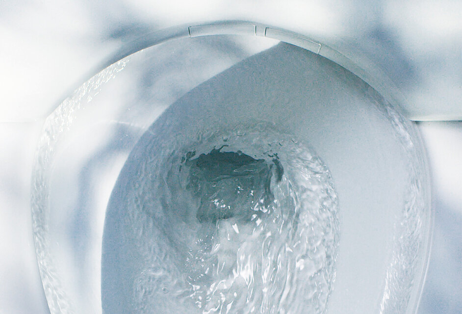 Einblick in die Toilettenkeramik von oben. Das Wasser fließt spiralförmig in den Abfluss hinein.