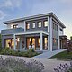 The photo shows a modern two-storey house at dusk, with interior lighting that creates an inviting ambience. The house is surrounded by a well-tended garden landscape with lavender in bloom in the foreground, and has a spacious terrace with seating.